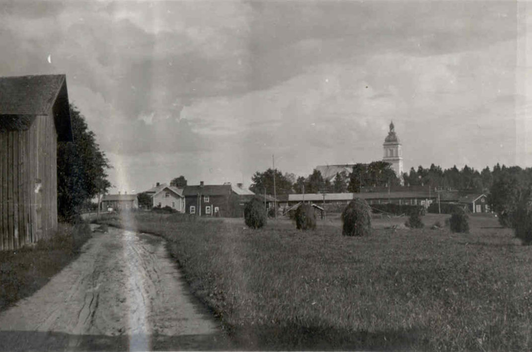 Leppävirran kirkonkylän maisema etualalla tie ja peltoa taustalla näkyy Leppävirran kirkko.