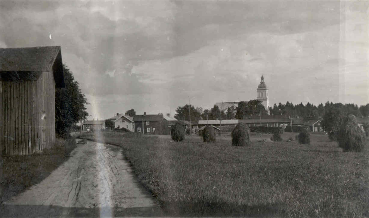 Leppävirran kirkonkylän maisema etualalla tie ja peltoa taustalla näkyy Leppävirran kirkko.