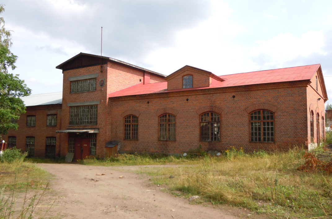 Suuri punatiilinen teollisuusrakennus jossa suuret ikkunat.