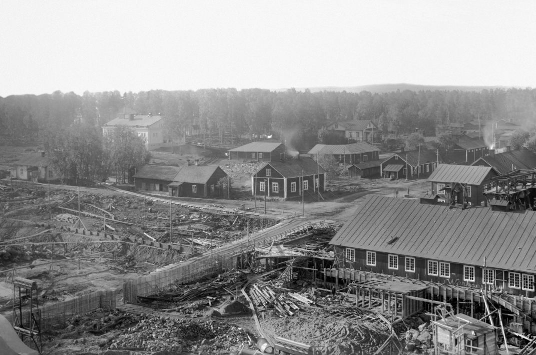 Korkealta otettu kuva rakennustyömaasta jossa kaivettua maata ja silta sekä työmaan ympäristössä rakennuksia