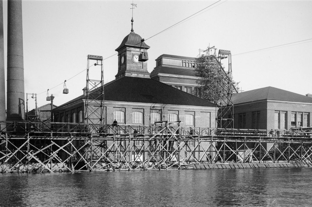 Veden äärellä sijaitseva tiilinen rakennus jonka katolla torni jossa kello