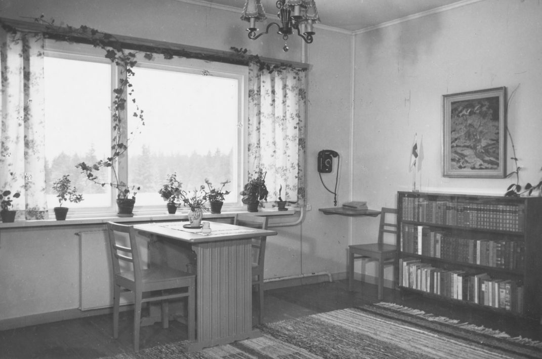 Sisäkuva asunnosta kuvassa pöytä ikkunan edessä ja kirjahylly seinällä